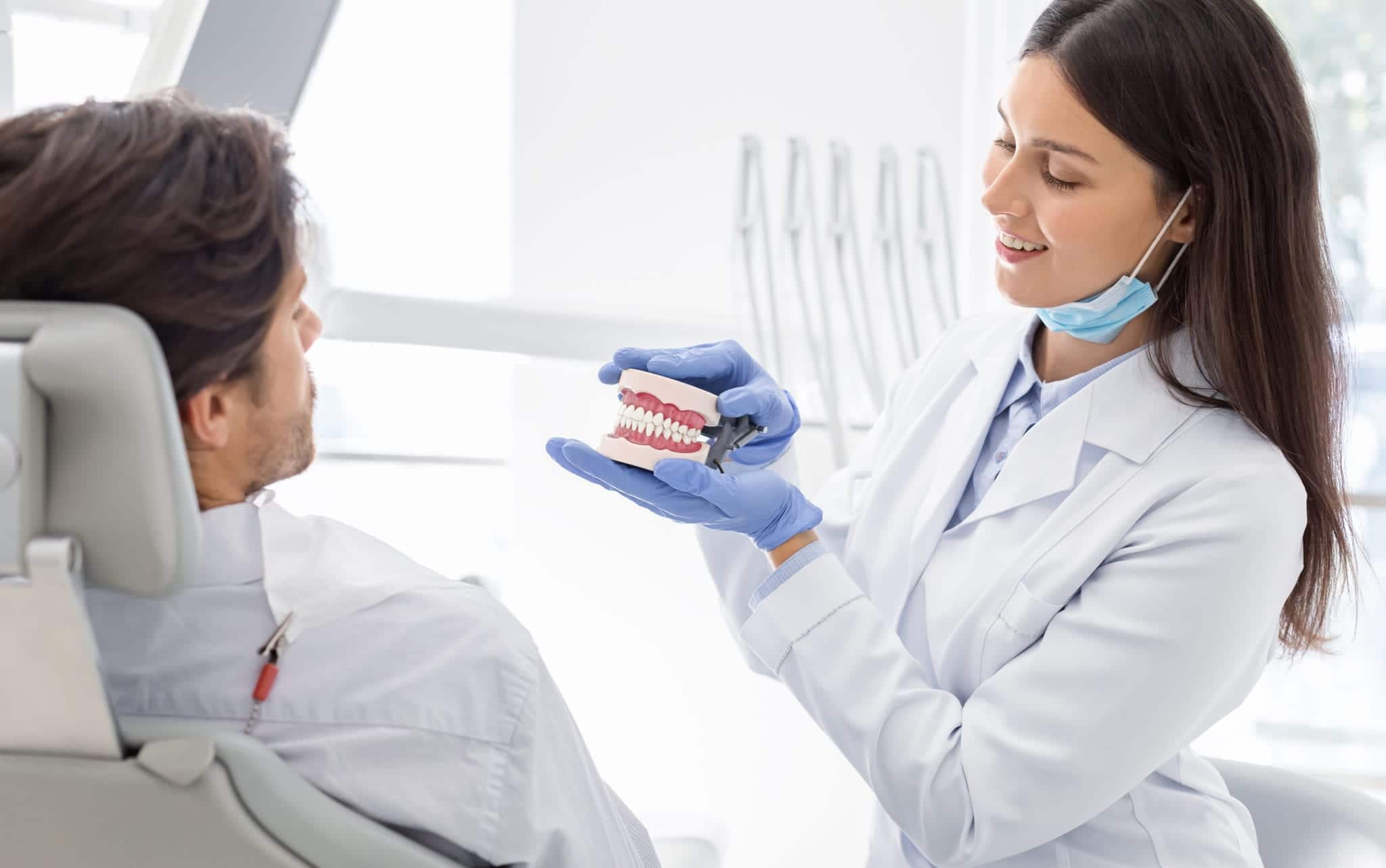 Pretty dentist showing her patient jaw model