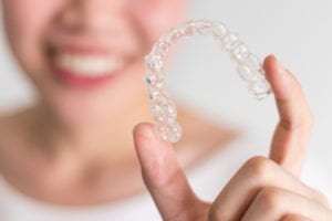 close up of woman holding Invisalign tray with blurred background