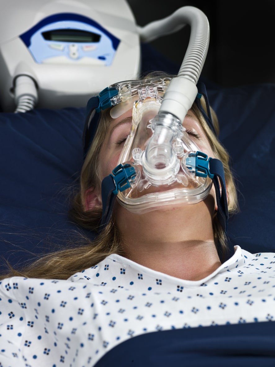 close up picture of a caucasian young woman sleeping wearing an apnea mask on black background (this picture has been taken with a Hasselblad H3D II 31 megapixels camera)