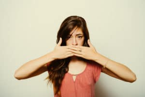 girl covers her mouth with her hands