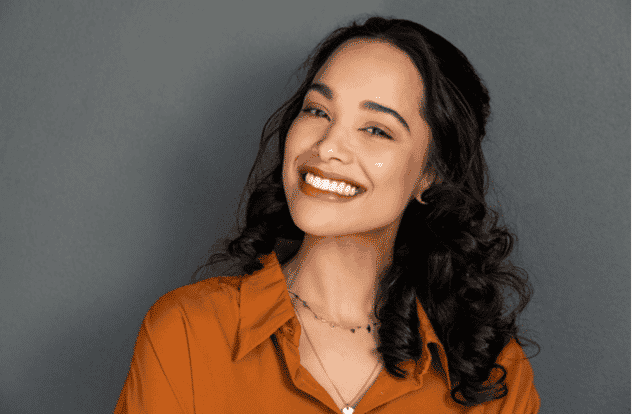 young woman with beautiful smile on grey wall