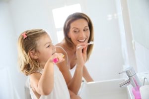Mother and daughter in bathroom brushing her teeth 1