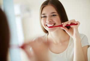 Young woman brushing her teeth at mirror